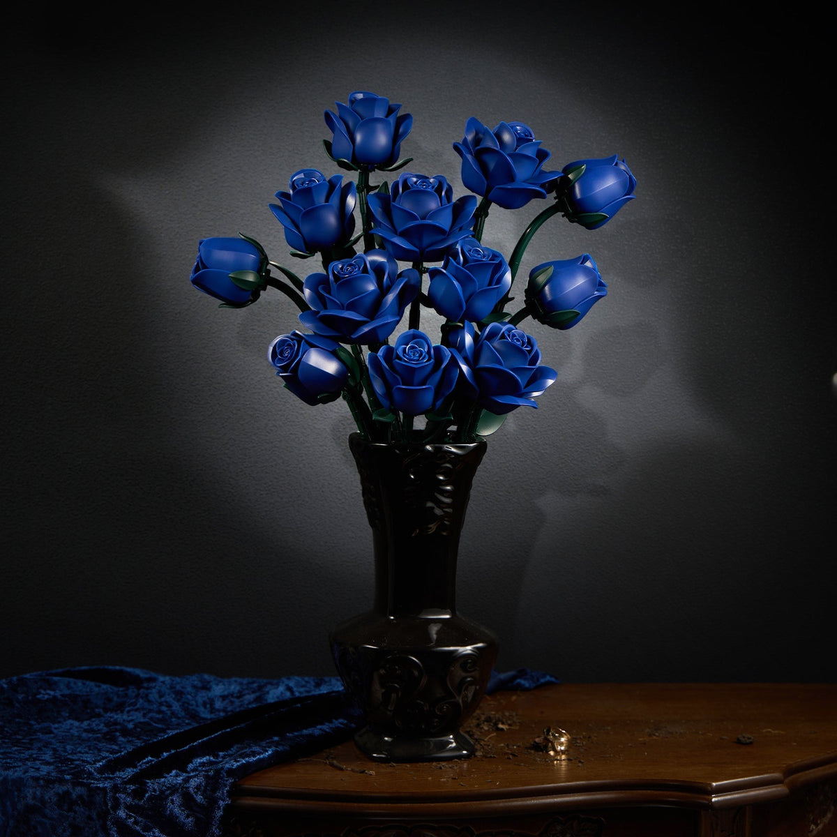 Blue rose bouquet in a carved dark vase with blue velvet drapery