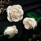 Two white roses on black velvet - one open bloom and one bud, with glossy green leaves