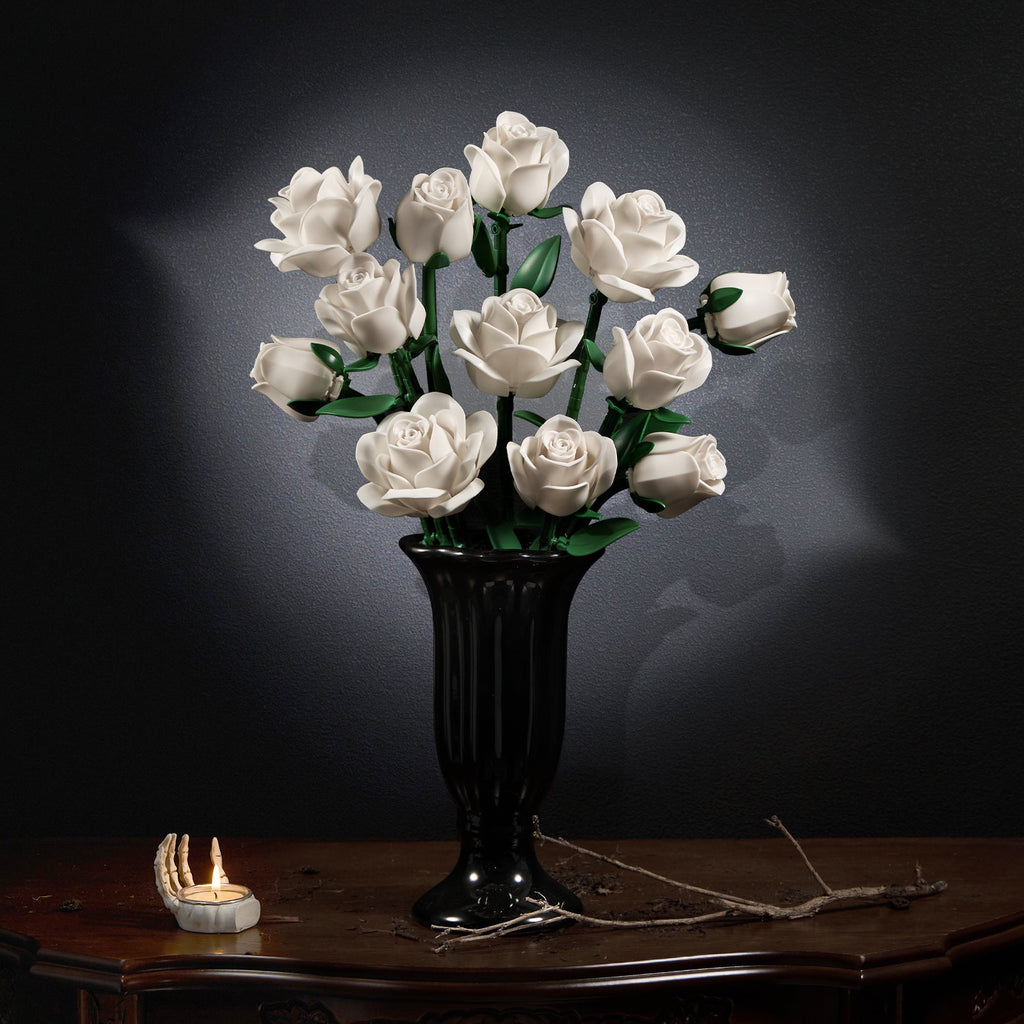 White rose bouquet in a carved black vase on an antique table against a dark background