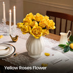 Yellow roses in a white vase on a laid dining table with lit candles